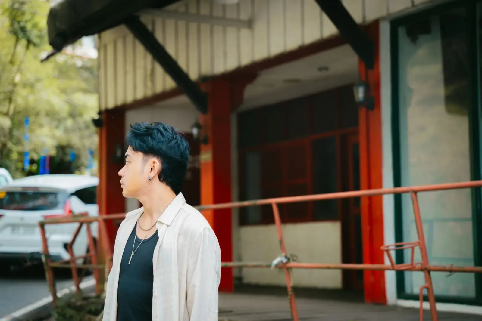 Người đàn ông trẻ mặc đồ giản dị đứng nhìn nghiêng giữa phố
