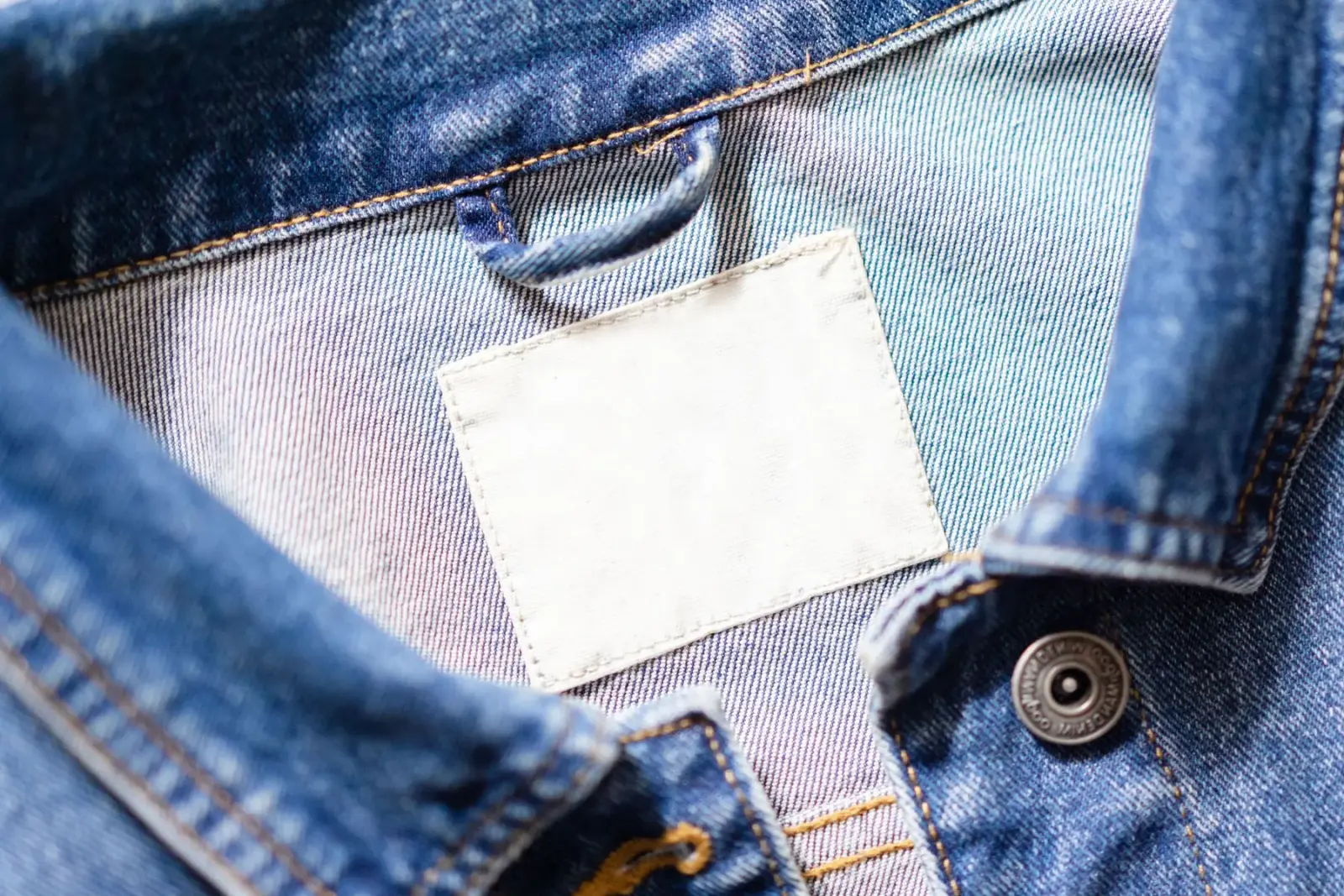 Cận cảnh cổ áo khoác denim với miếng nhãn trắng còn trống
