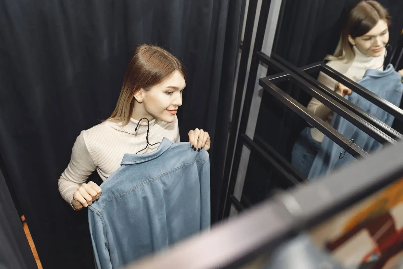 Người phụ nữ mặc quần jean ống rộng đứng trước gương