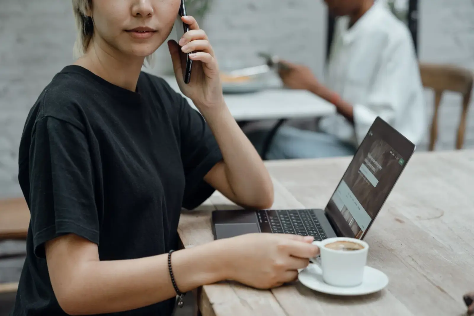 Người phụ nữ mặc áo thun đen vừa gọi điện vừa làm việc