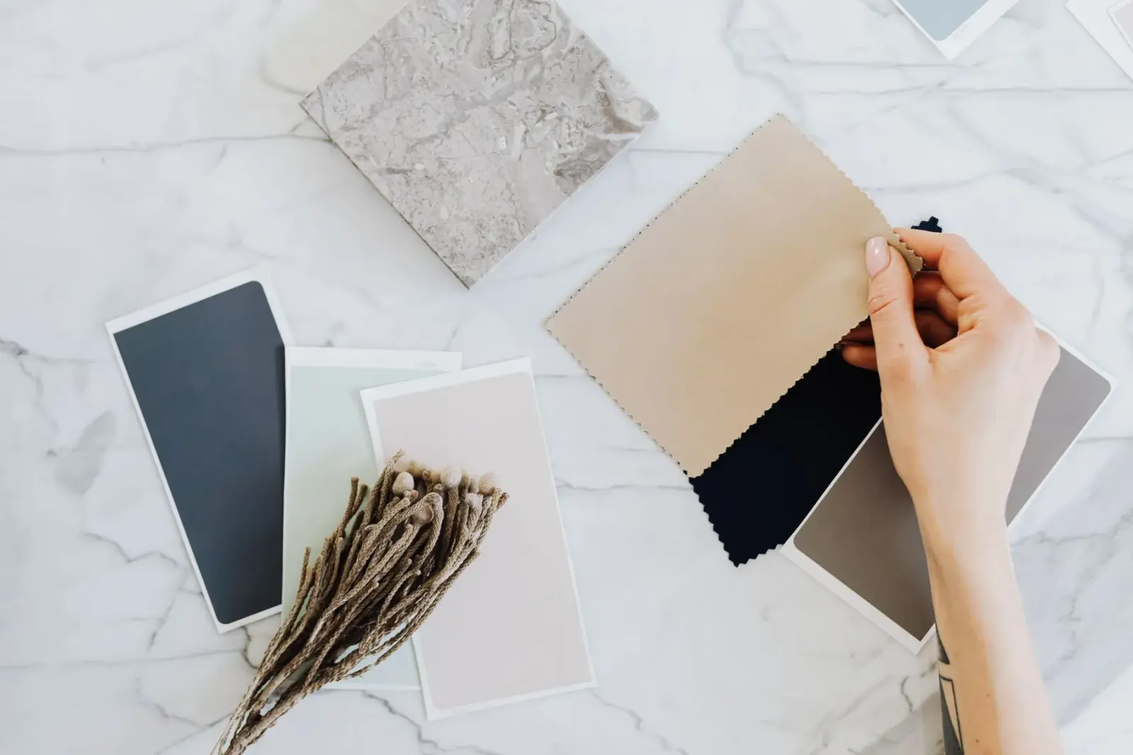 Đôi tay cầm các mẫu vải kèm bảng màu