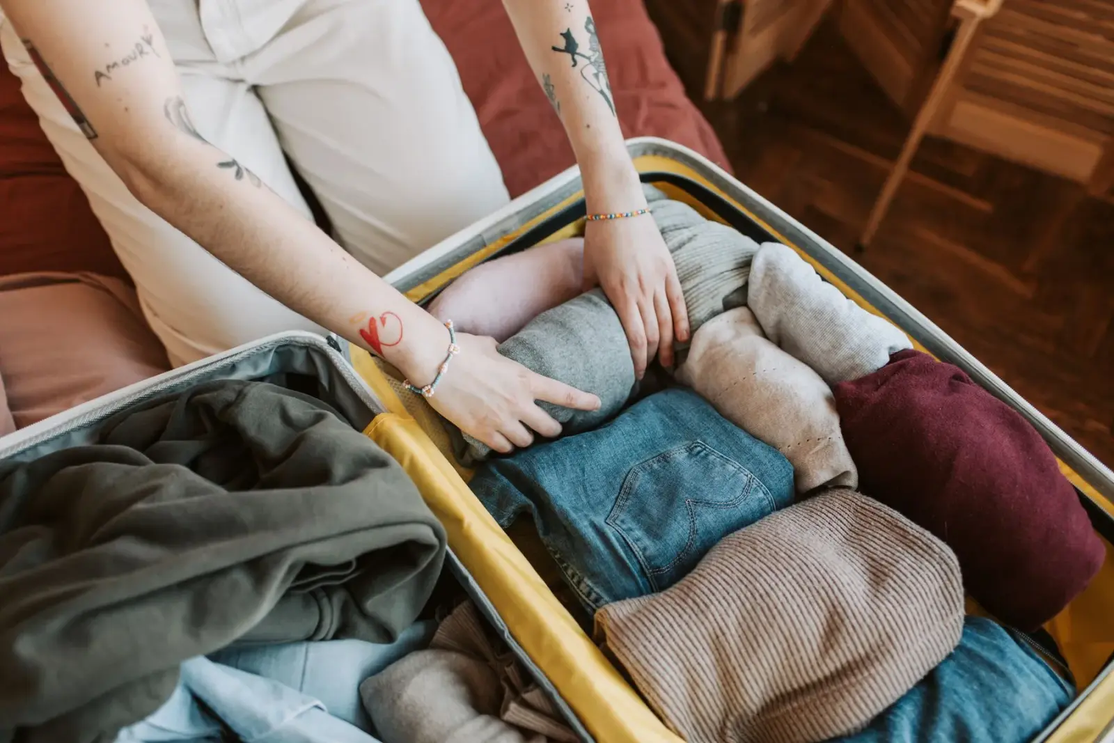 Cận cảnh đôi tay xếp quần áo vào vali