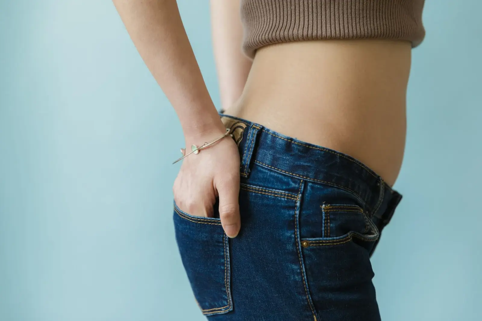 Cận cảnh vòng eo trong áo croptop và quần jean xanh