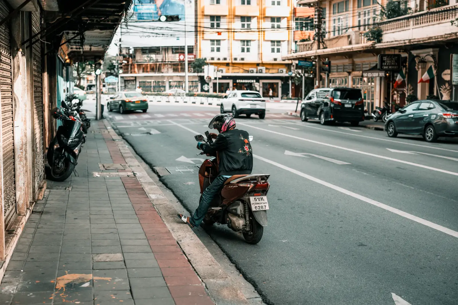 Xe máy đỗ bên lề một con phố đông xe qua lại