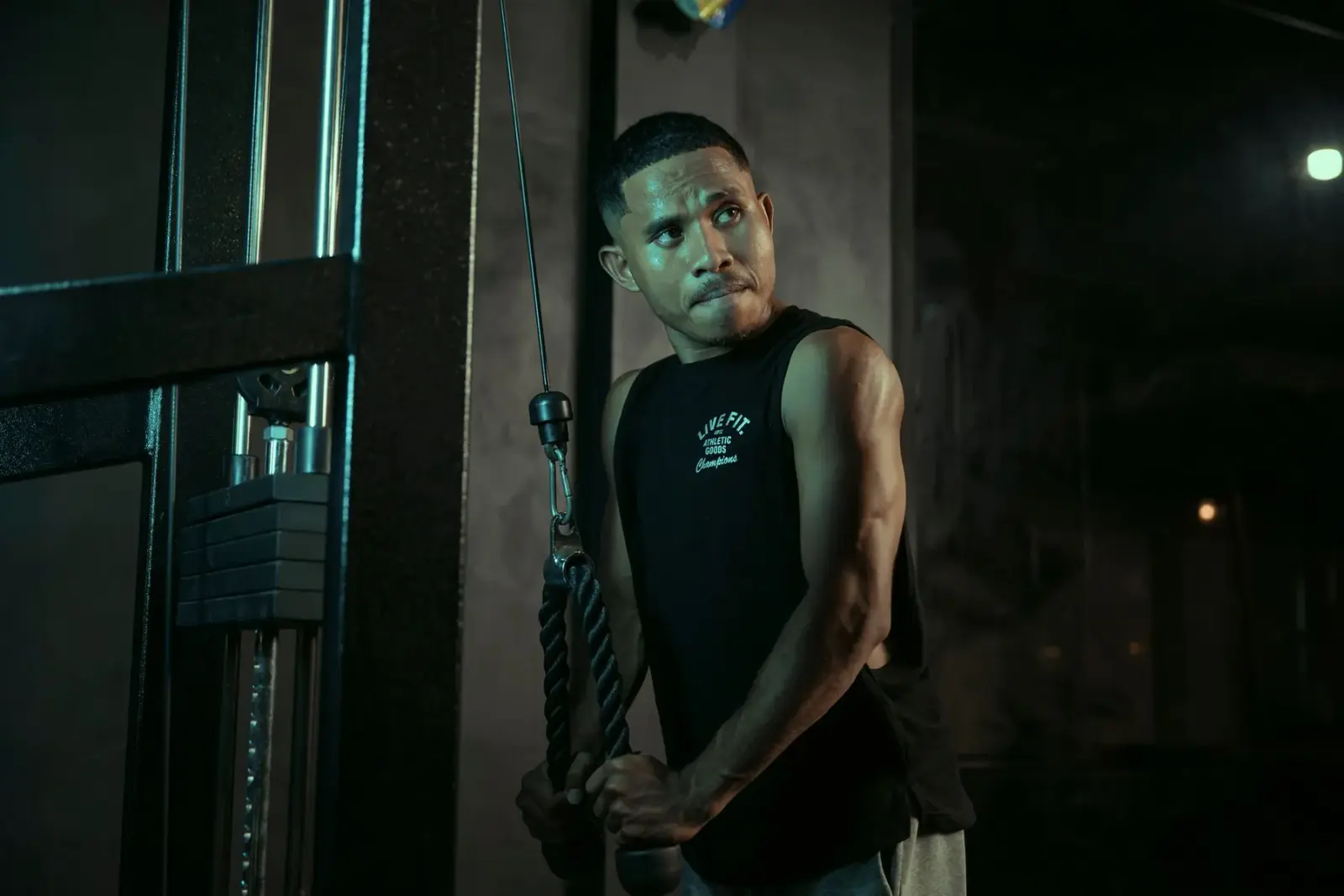 Người đàn ông tập với máy kéo cáp trong phòng gym